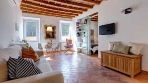 A living room with a wooden ceiling, a sofa, a coffee table, a TV, and a bookshelf. - Casa Modelli (Rome)