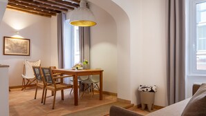 A dining area with a wooden table and chairs, a hanging light fixture, a framed map on the wall, and a window with curtains. - Casa Modelli (Rome)