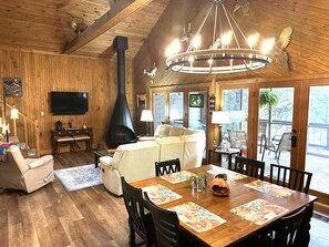 Ein gemütliches Wohnzimmer mit Kamin, einer Couch, einem Fernseher und einem Essbereich mit Tisch für vier Personen.