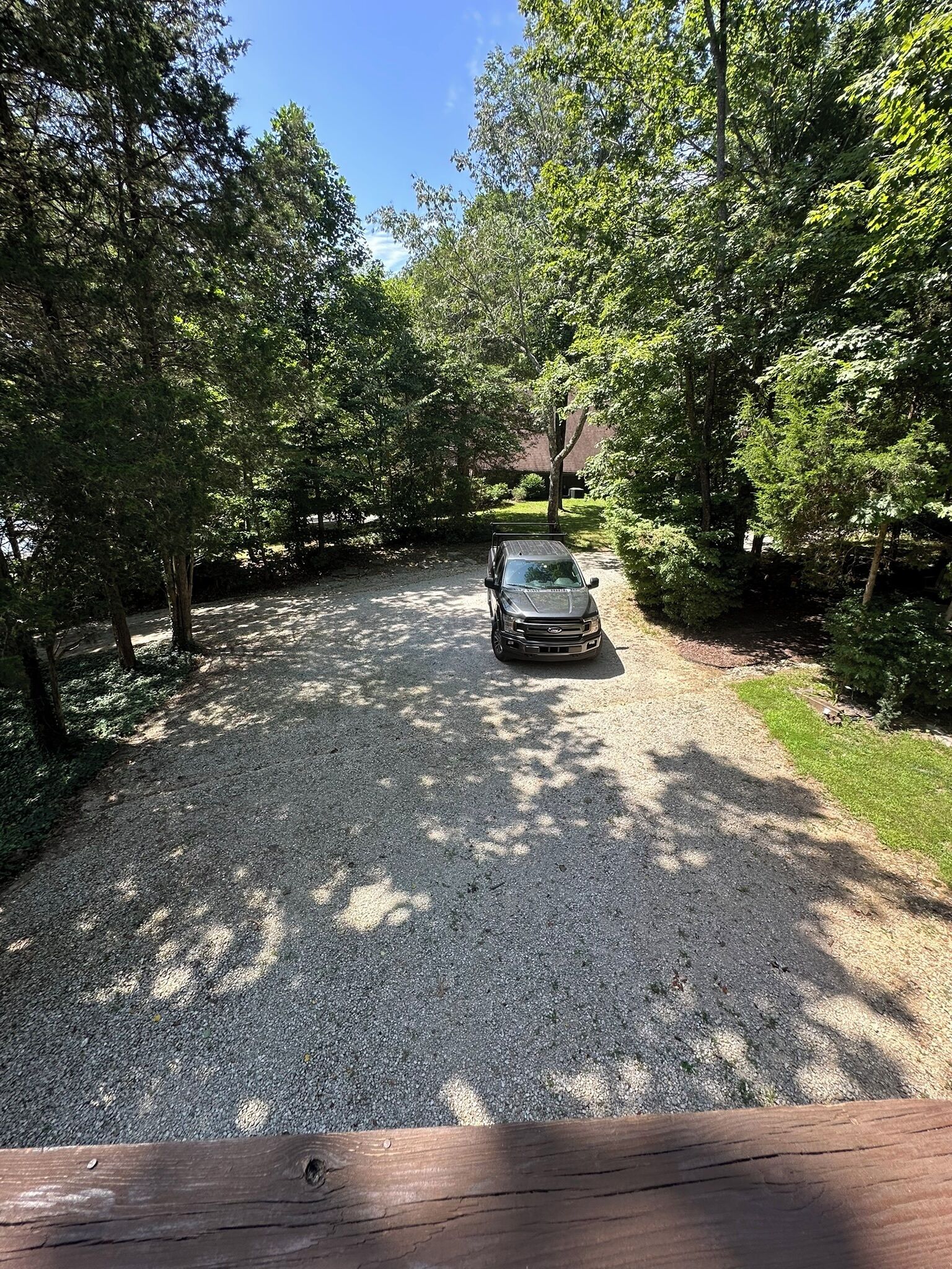 A gravel driveway leading to a vehicle parked in a wooded area.