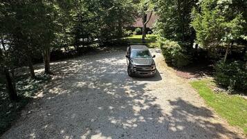 A gravel driveway leading to a vehicle parked in a wooded area.