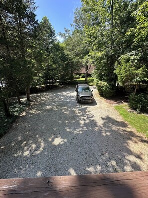 A gravel driveway leading to a vehicle parked in a wooded area.