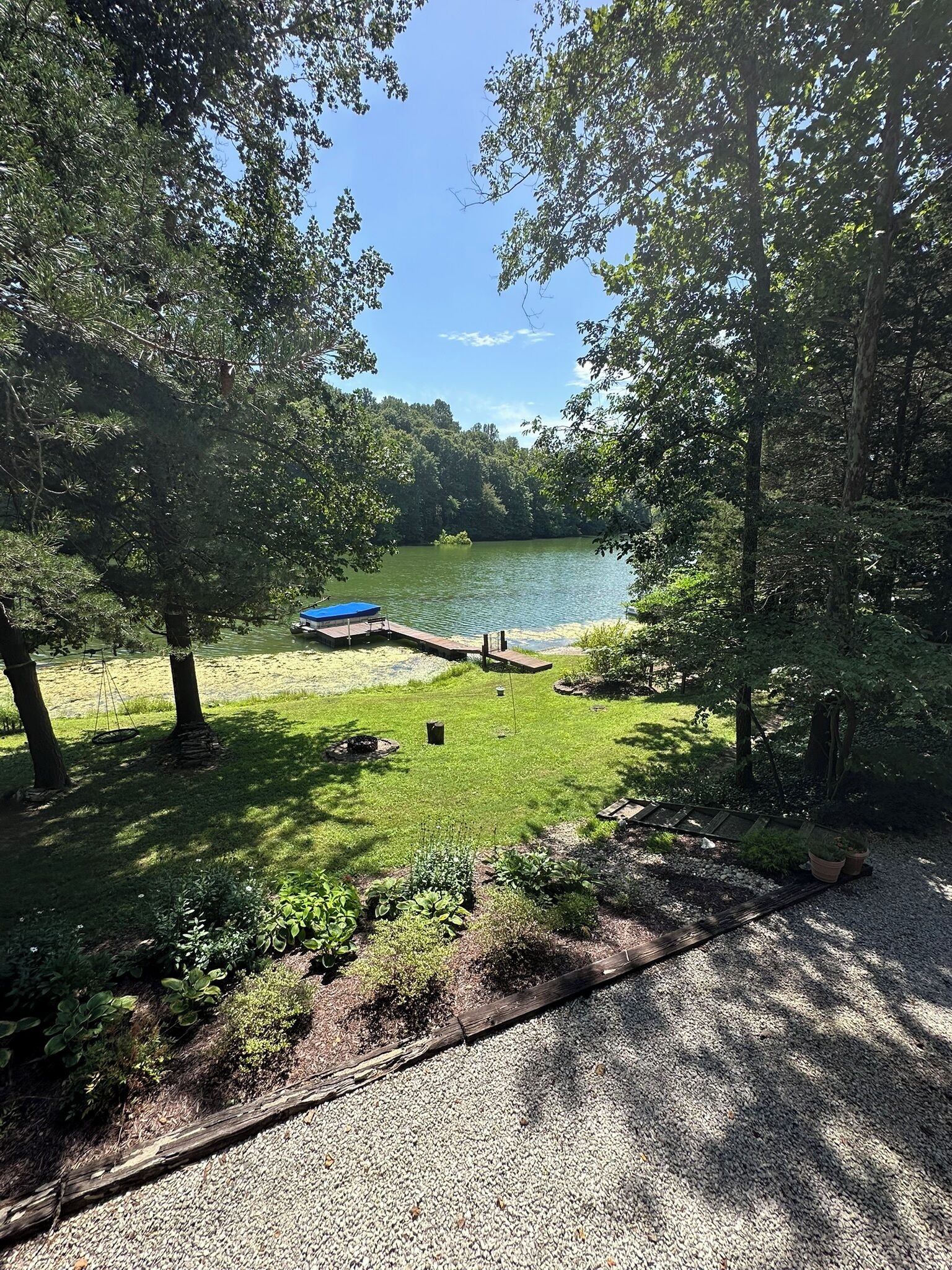 Un terrain de camping au bord du lac, doté d’un quai, d’une zone herbeuse et d’arbres.