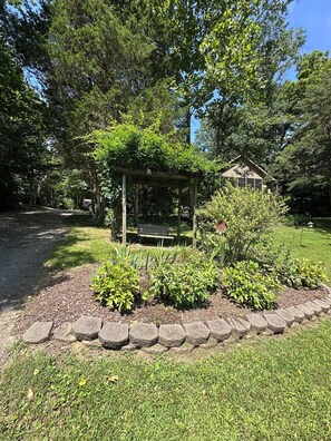 A garden area with a wooden pergola, a bench, and a small gazebo.