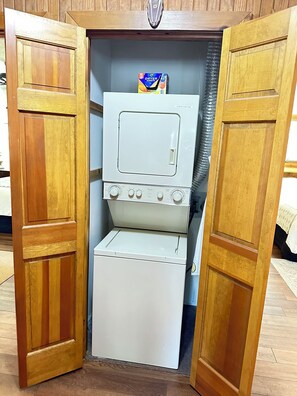 A compact, white, two-door cabinet with a microwave and a small refrigerator inside.