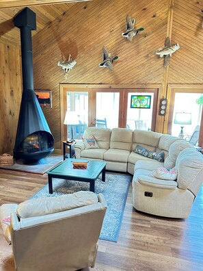 Una sala acogedora con chimenea, techo de madera y asientos cómodos.
