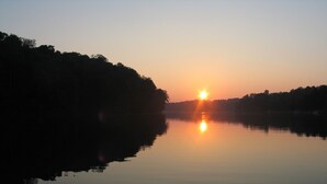 Un lago tranquilo al amanecer con árboles en la orilla.