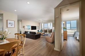 Relax in this stylish living area with a sofa, armchair, and dining table, offering a view of the ocean from the balcony.
