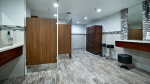 Ein modernes Badezimmer mit einer Holzwand, einem großen Spiegel und einem Barhocker.
