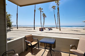 Relax on the balcony with a view of the beach, featuring two chairs and a table.