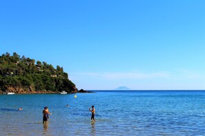 A coastal scene with clear skies, calm sea, and a distant mountain. - Il Guercino (Capoliveri)