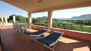 Un espace extérieur abrité, doté de chaises longues et d’une table, offrant une vue sur un paysage pittoresque.
