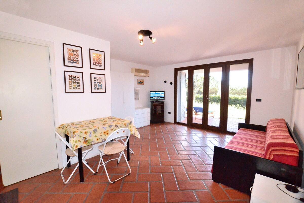 A room with a dining table, a bed, and a TV. There are four framed pictures on the wall.