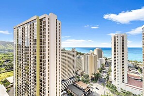 A high-rise hotel with multiple floors, a parking area, and a view of the ocean.