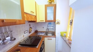 A compact kitchen with a sink, stove, and a small refrigerator. - La Piaggia (Rio)
