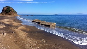A beach with pebbles, a large rock, and a cliff. - Le Maree Fede (Rio)