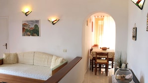 A living room with a sofa, a dining table with chairs, and a decorative bowl on a table. - Le Maree Fede (Rio)