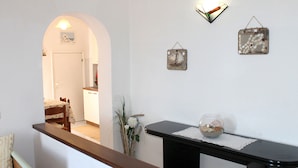 A hallway with a wooden bench, a small table with a glass bowl, and a wall with two decorative items. - Le Maree Fede (Rio)
