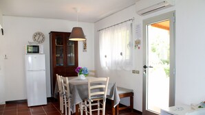 A compact kitchen with a refrigerator, microwave, and dining table set for four. - Scaglieri Mare (Portoferraio)
