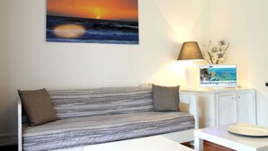 A room with a striped sofa, a lamp, a framed picture of a sunset, and a sign on a table. - Scaglieri Mare (Portoferraio)
