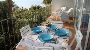 A balcony with a table set for dining, overlooking a coastal view. - Scaglieri Mare (Portoferraio)
