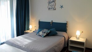 A bedroom with a bed, two bedside tables, a nightstand, a wall decoration, and a window with curtains. - Scaglieri Mare (Portoferraio)