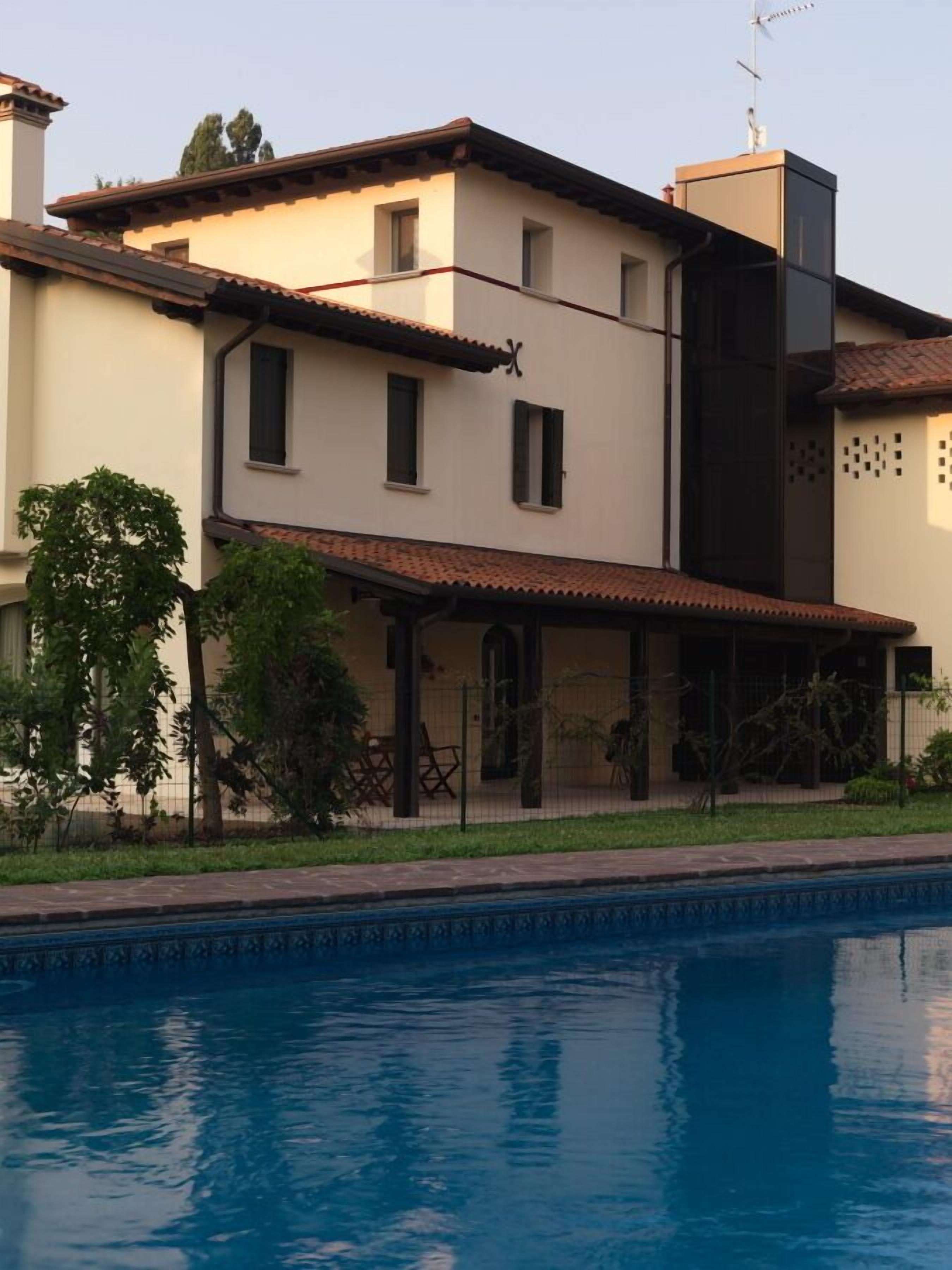 A two-story house with a swimming pool in the foreground.
