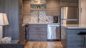 Une cuisine moderne dotée d’appareils électroménagers en acier inoxydable, de meubles en bois et d’un revêtement mural en carreaux.