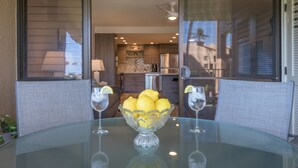 Une table en verre avec un saladier rempli de citrons et deux verres d’eau.