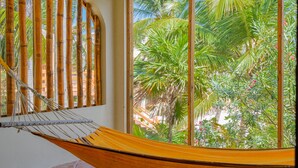 A hammock in a room with a view of palm trees through a window with bamboo blinds. - San Pedro 5-bedroom, 4-bathroom Villa Pearl, ocean views, concierge onsite (San Pedro)