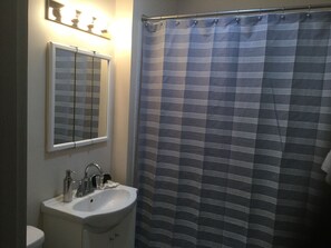 A bathroom with a sink, mirror, and striped shower curtain.