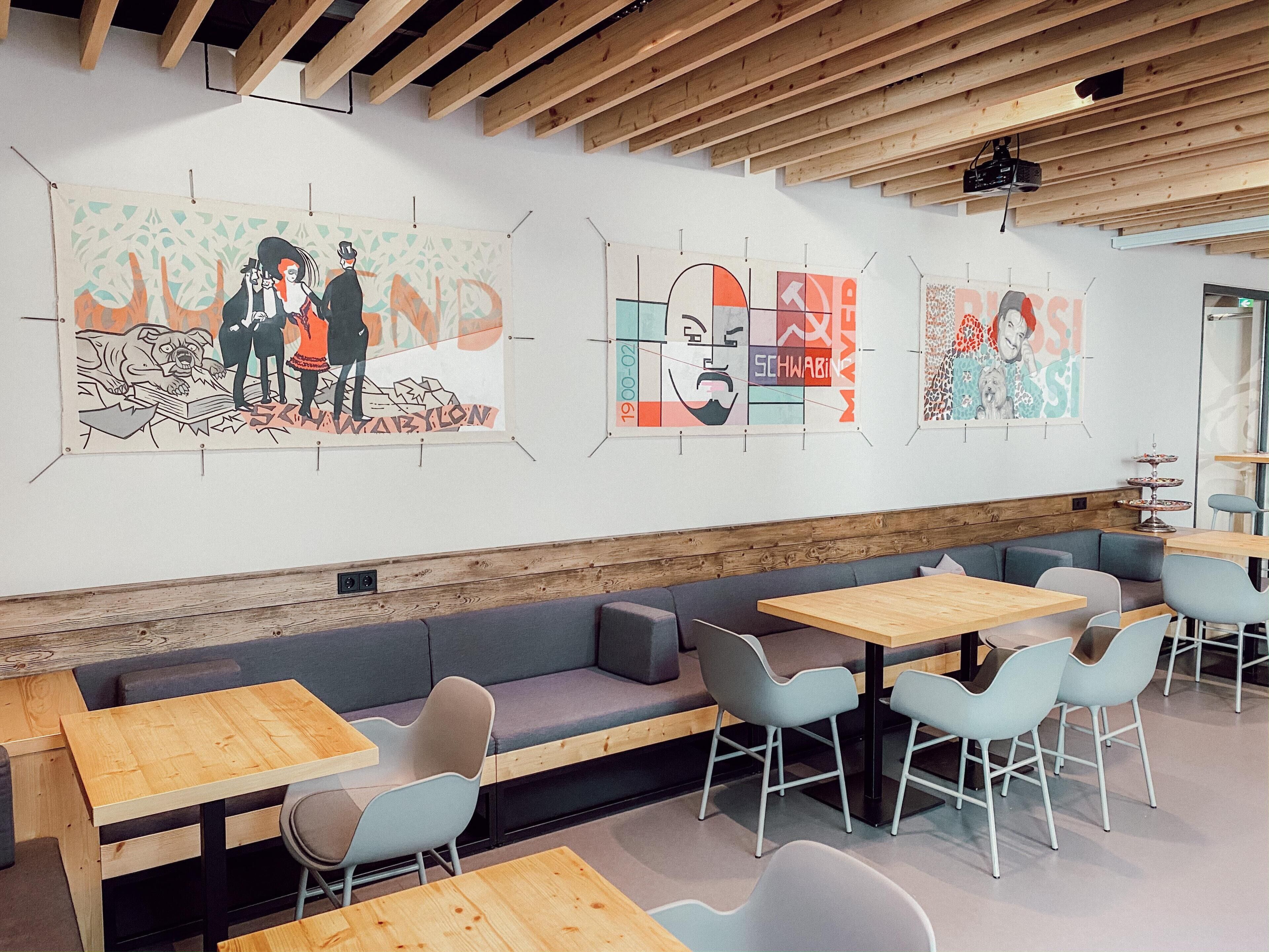 A modern interior with wooden beams, a long bench, and tables with chairs.