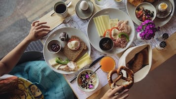 Una mesa de desayuno con platos de comida, un croissant y un vaso de jugo de naranja.