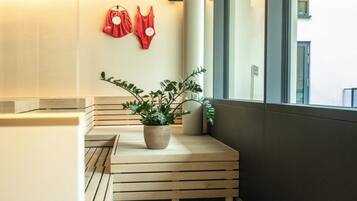 Rincón con un banco de madera, una planta en maceta y dos bolsas rojas colgadas en la pared.