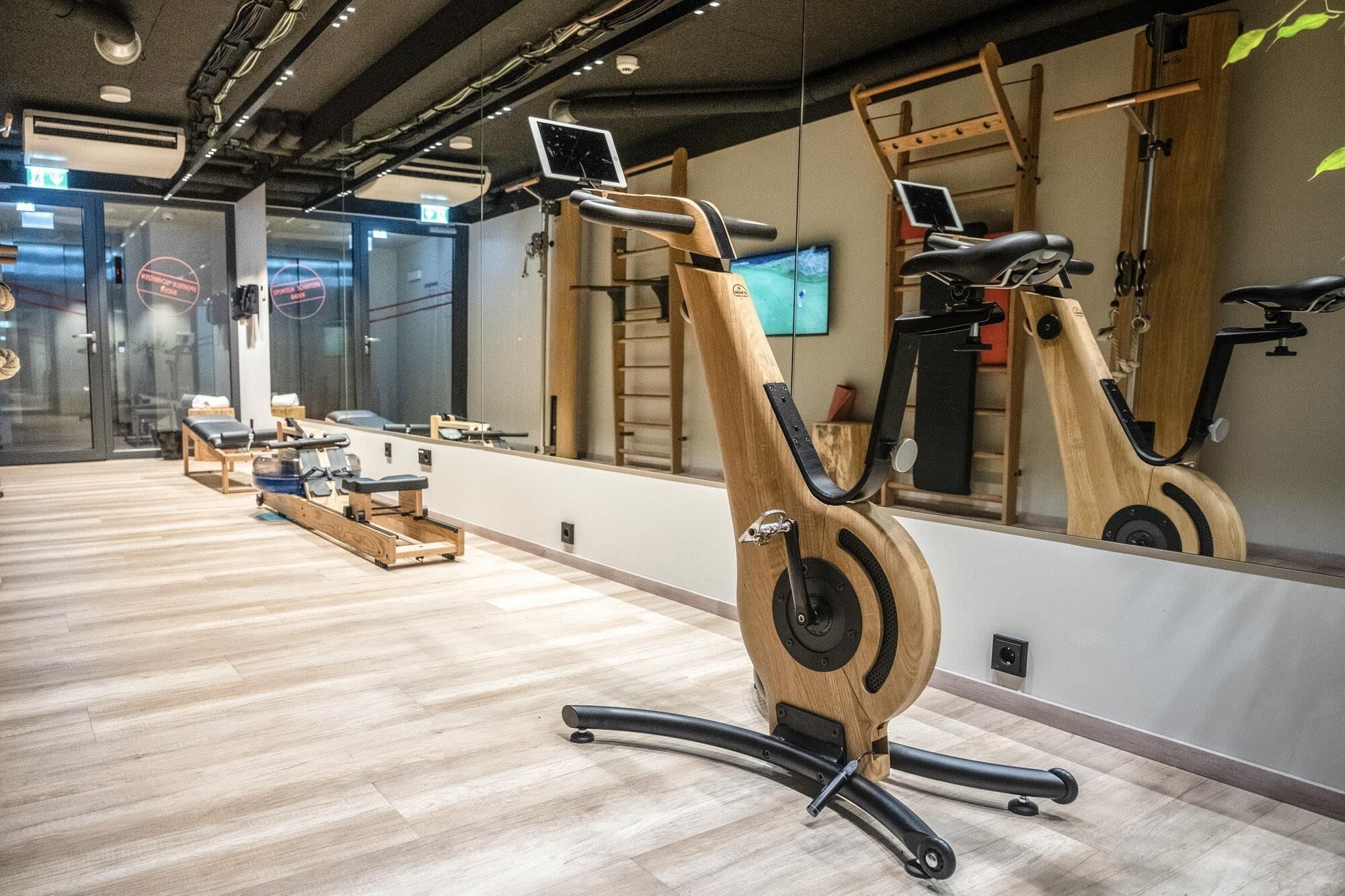 A gym with exercise equipment, mirrors, and a wooden floor.