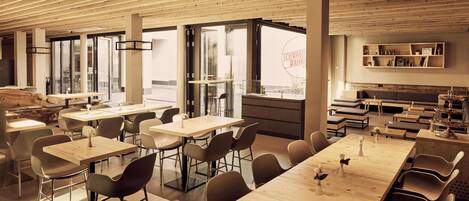 Un comedor moderno con mesas y sillas de madera, ventanas amplias y vistas a la ciudad.