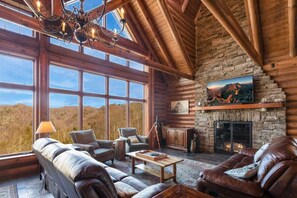 Enjoy a panoramic view from the large windows in this well-appointed living room with a stone fireplace and comfortable seating.