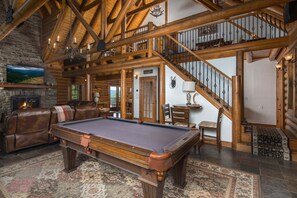 A spacious living area with a pool table, leather seating, a fireplace, and a staircase leading to an upper level. - Private Mountaintop Retreat | Hot Tub, Sauna, Game Room & Views (Sugar Grove)