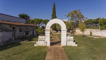 A courtyard with a stone archway leading to a building with a tiled roof.