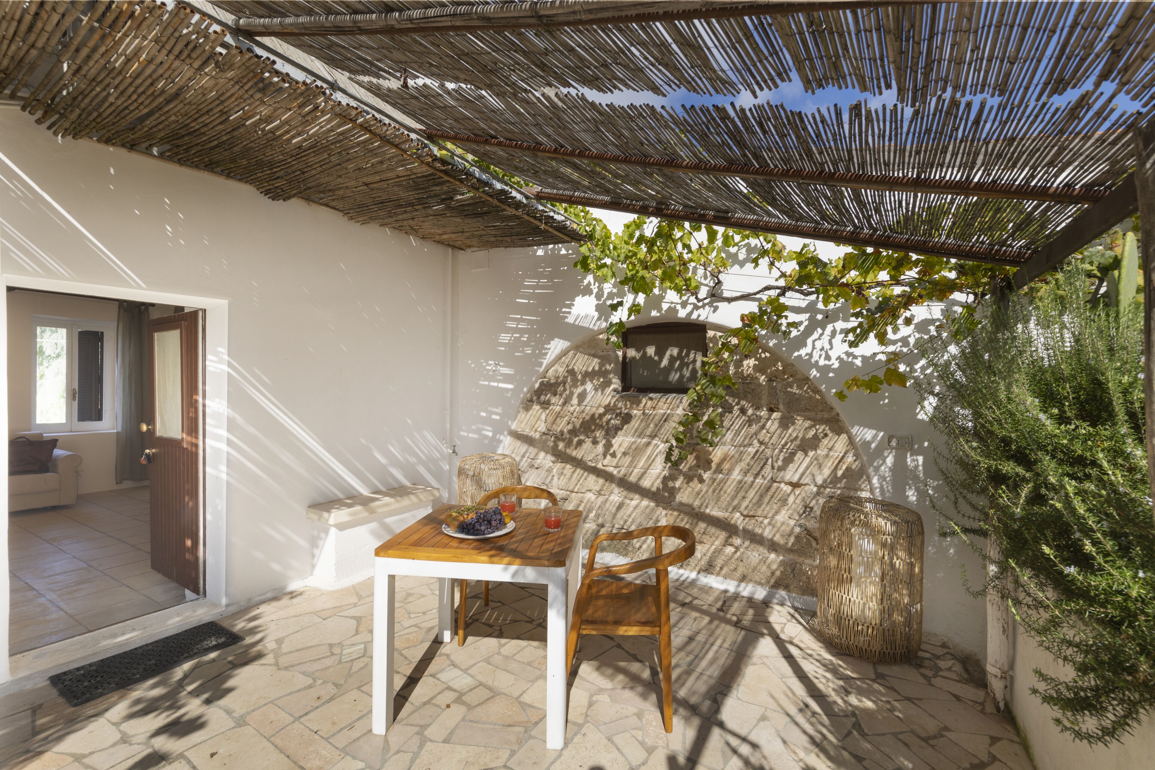 An outdoor patio with a table and chairs, a woven basket, and a potted plant.