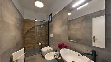 Un baño moderno con cabina de ducha de vidrio, un lavabo blanco y un bidé.