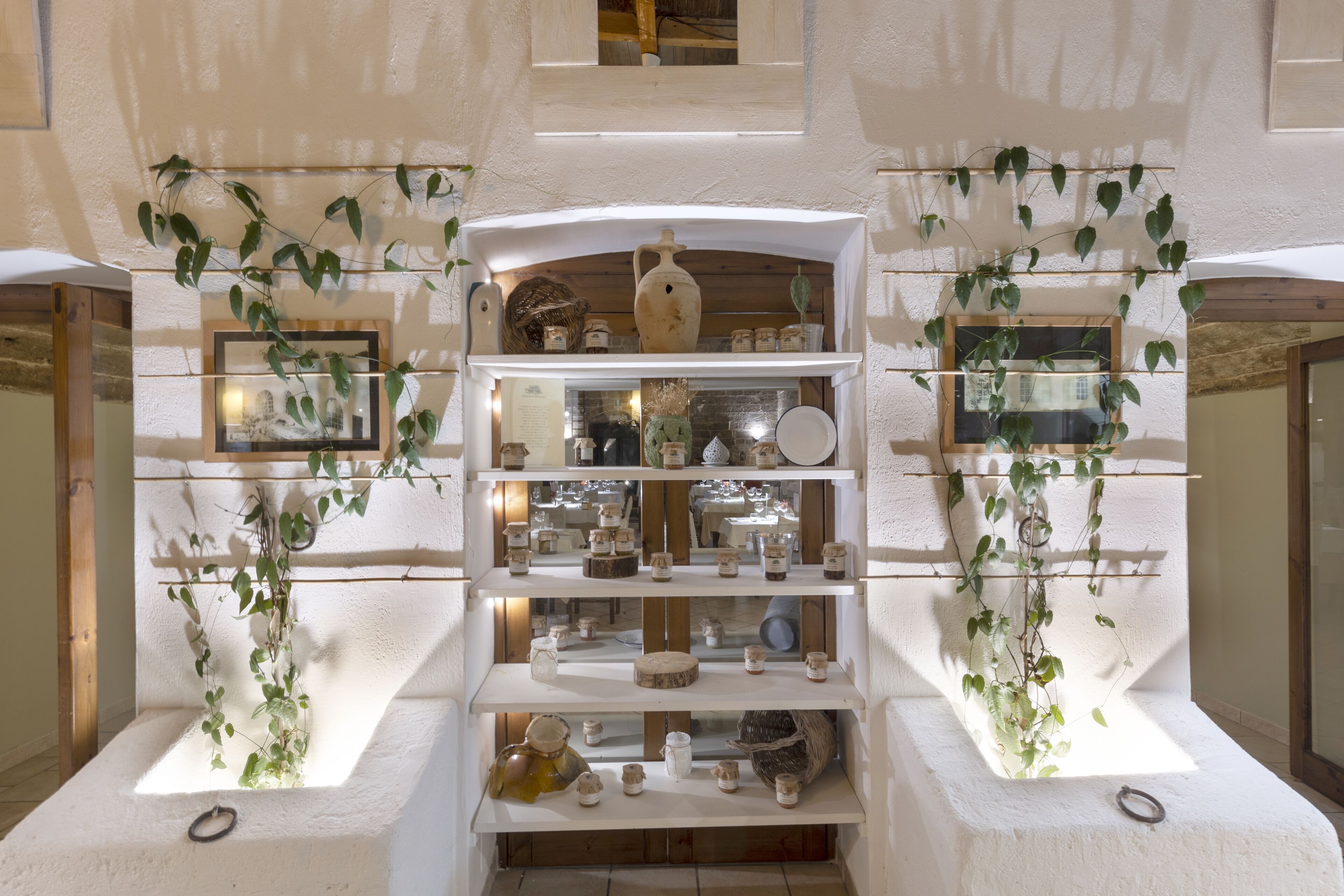 A multi-level display of ceramics and pottery in a rustic interior with white walls and wooden beams.