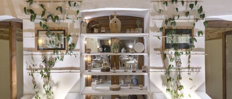 A multi-level display of ceramics and pottery in a rustic interior with white walls and wooden beams.
