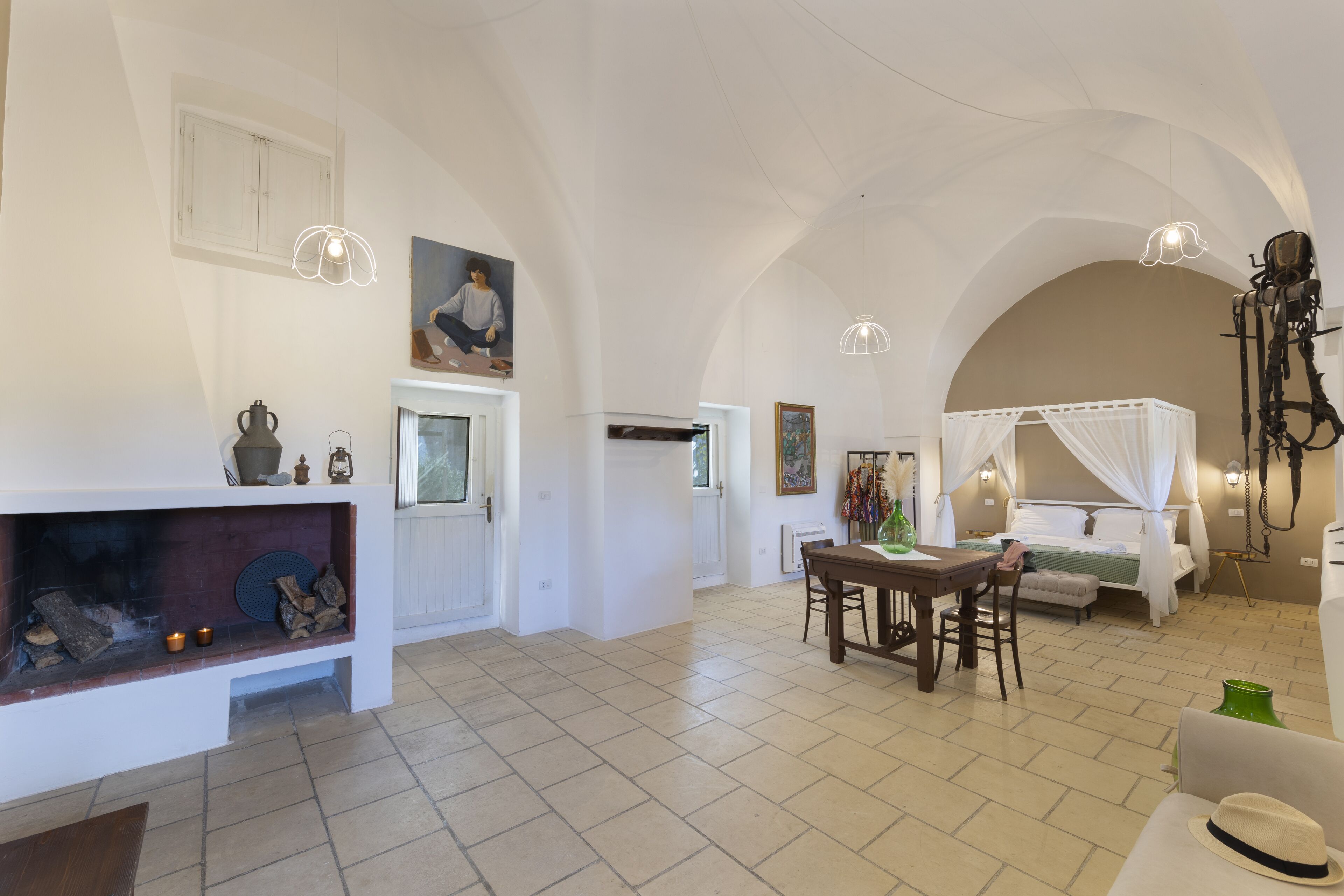 A spacious living area with a fireplace, dining table, and a bed with a canopy.