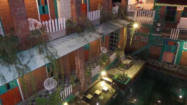 Ein mehrstufiger Innenhof mit Außenbereich, Sitzgelegenheiten, einem Pool und einem Restaurant, das durch die Fenster sichtbar ist.