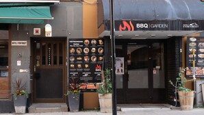 A restaurant with a BBQ Garden sign, a menu board, and a sign for Hotel Stortorget. - Hotell Stortorget (Östersund)