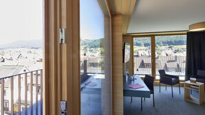 Una habitación de hotel moderna con balcón, comedor y vistas del paisaje circundante.
