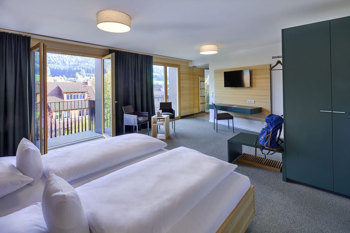 A hotel room with two beds, a desk, a chair, a TV, and a wardrobe.