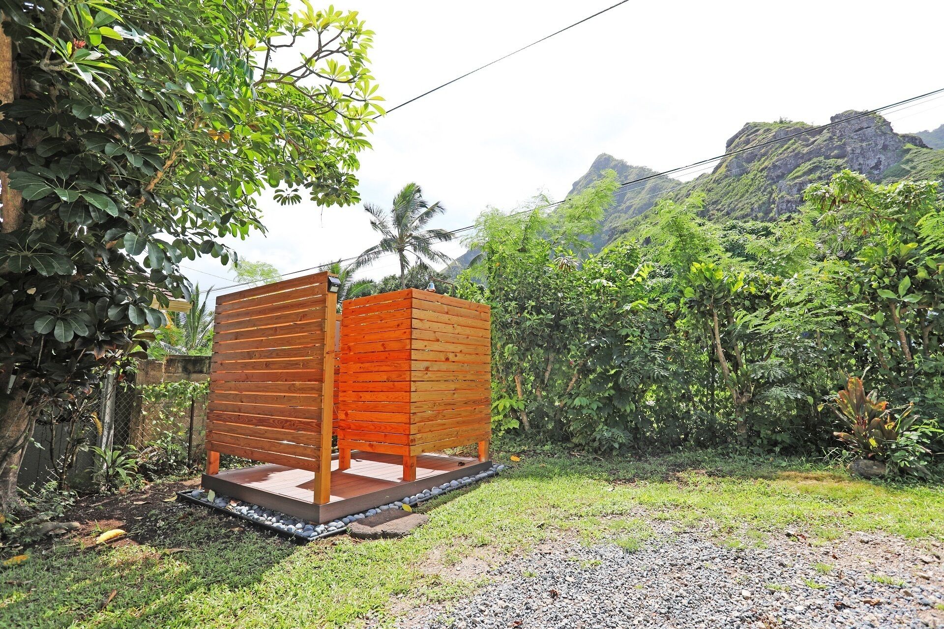 A wooden structure with a platform, surrounded by lush greenery and a mountainous backdrop.