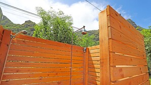 Una reja de madera con un tirador de metal, frente a un fondo de exuberante vegetación y montañas.